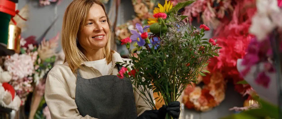 Artikelbild2 1136×480.webp Florist binder en bukett i sin blomsterbutik
