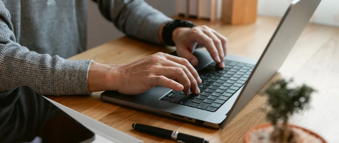 Händer skriver på en laptop vid ett skrivbord
