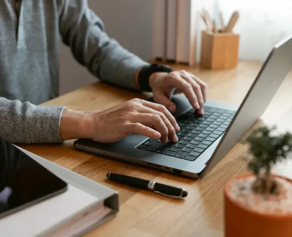 Händer skriver på en laptop vid ett skrivbord