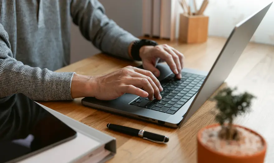 Händer skriver på en laptop vid ett skrivbord